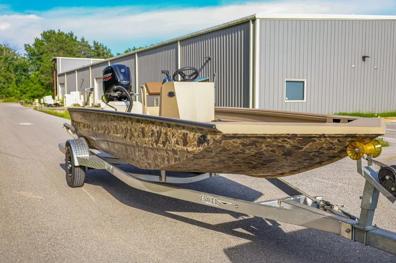 Slide: The Image of 2026 Excel Switchblade boat on trailer, camo design, parked near industrial building. - 5