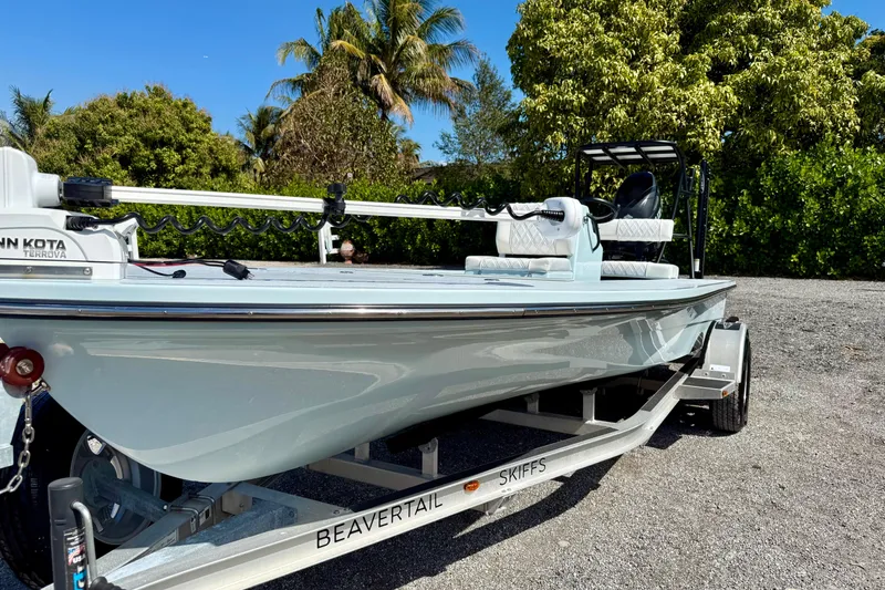 Slide: The Image of 2022 Beavertail Skiffs Vengeance 18 boat on trailer, surrounded by lush greenery. - 2