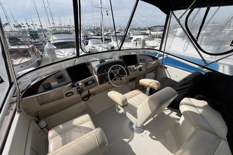 Slide: The Image of 2005 Carver 41 Cockpit Motor Yacht helm with marina view, featuring modern controls and seating. - 11
