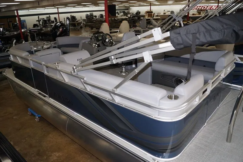 Slide: The Image of 2026 Avalon VLS Quad Lounge pontoon boat in showroom, featuring sleek design and spacious seating. - 2