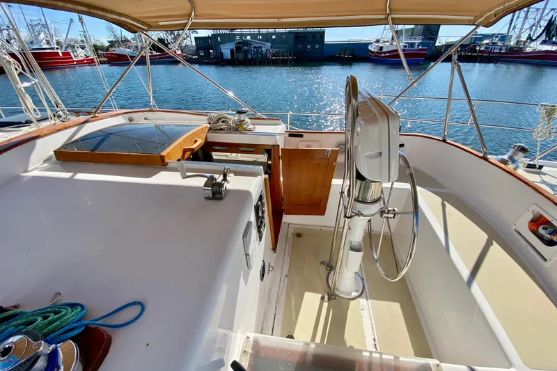 Slide: The Image of Cockpit of 1980 Wellington 44 sailboat with steering wheel, docked by the water. - 16