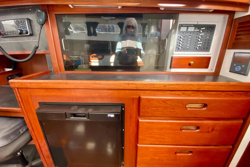 Slide: The Image of 1980 Wellington 44 yacht interior with wooden cabinetry, control panel, and mini fridge. - 26