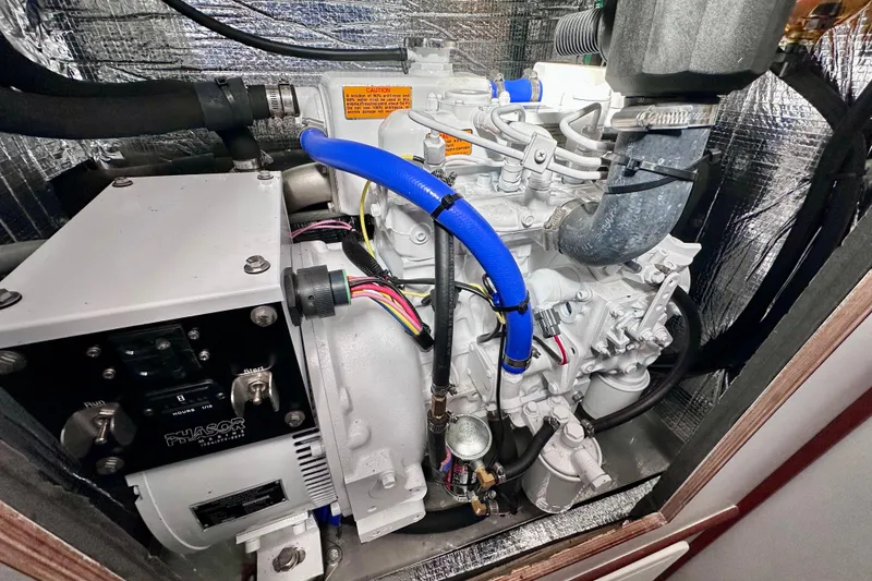 Slide: The Image of Engine compartment of a 1980 Wellington 44, featuring a Phasor generator and blue hoses. - 61