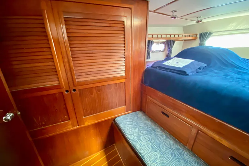 Slide: The Image of Cozy cabin interior of 1980 Wellington 44 yacht with wooden furnishings and blue bedding. - 63