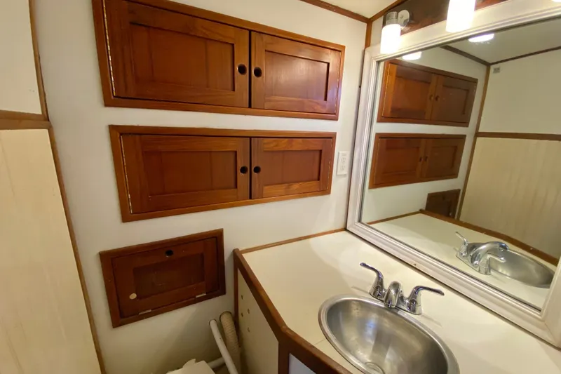 Slide: The Image of Compact bathroom with wooden cabinets, mirror, and stainless steel sink in a 1980 Wellington 44. - 67