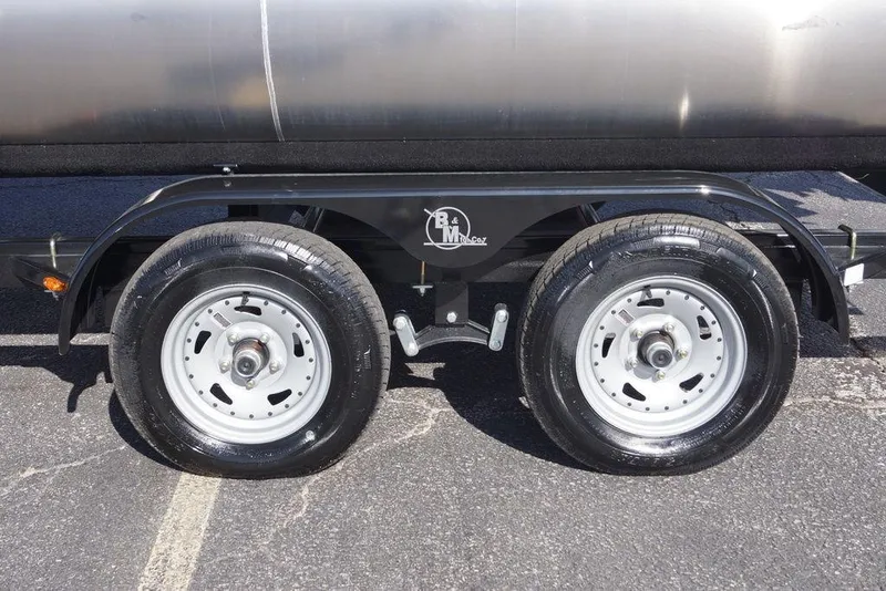 Slide: The Image of Trailer wheels of 2026 Avalon GS Quad Lounge - 18' on asphalt surface. - 3