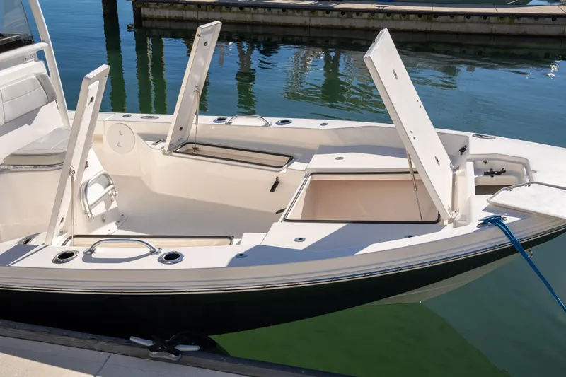 Slide: The Image of 2026 Bay Rider 239 Bay boat with open storage compartments at a marina. - 26