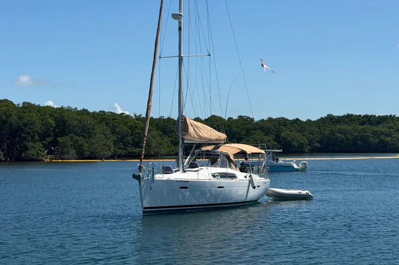 Slide: The Image of 2008 Beneteau Oceanis 40 sailboat anchored in serene waters with lush green backdrop. - 49