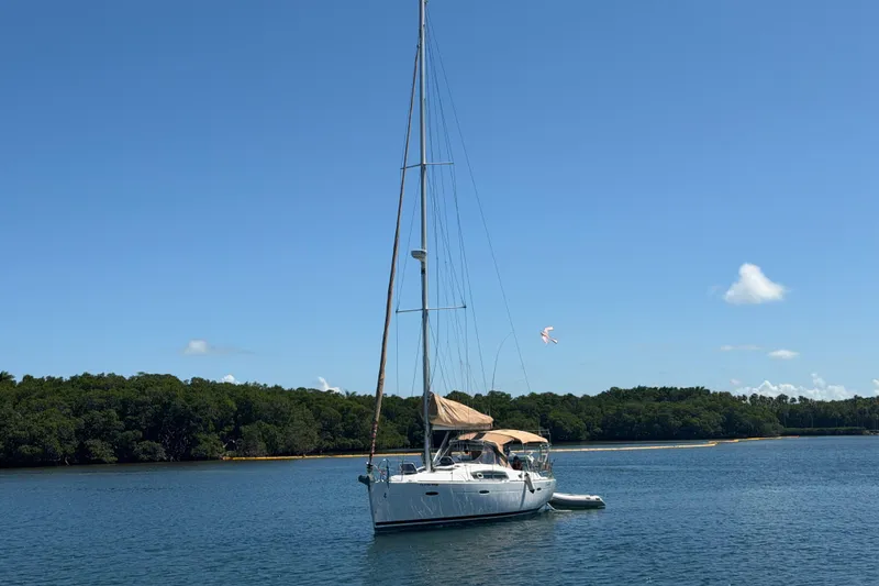 Slide: The Image of Sailboat Beneteau Oceanis 40, 2008 model, anchored in calm waters with lush green shoreline. - 50