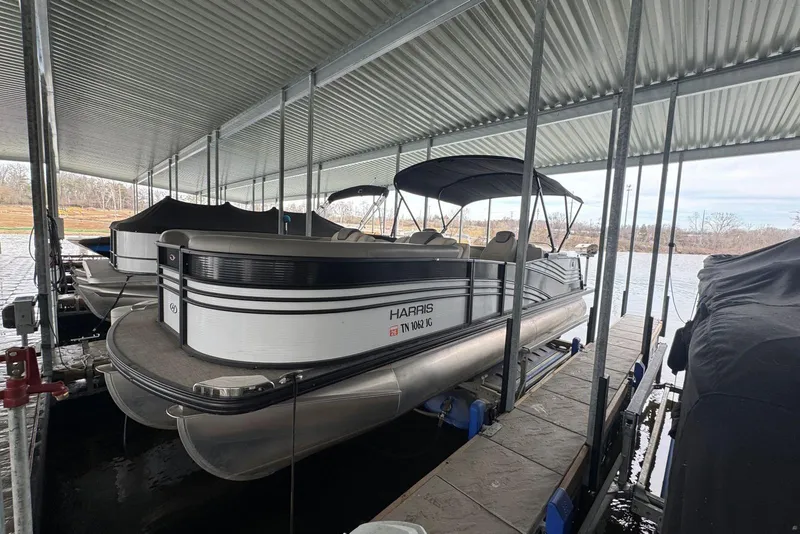 The Image of 2020 Harris Grand Mariner 250 pontoon boat docked under a covered marina. - 0