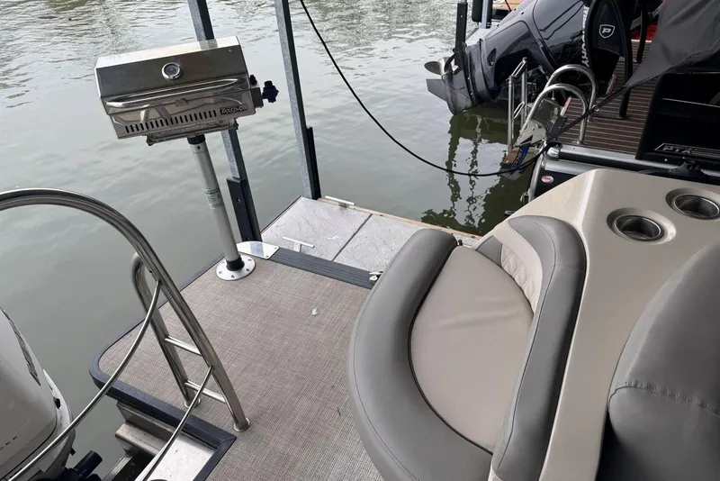 Slide: The Image of 2020 Harris Grand Mariner 250 boat with grill and seating area by the water. - 26