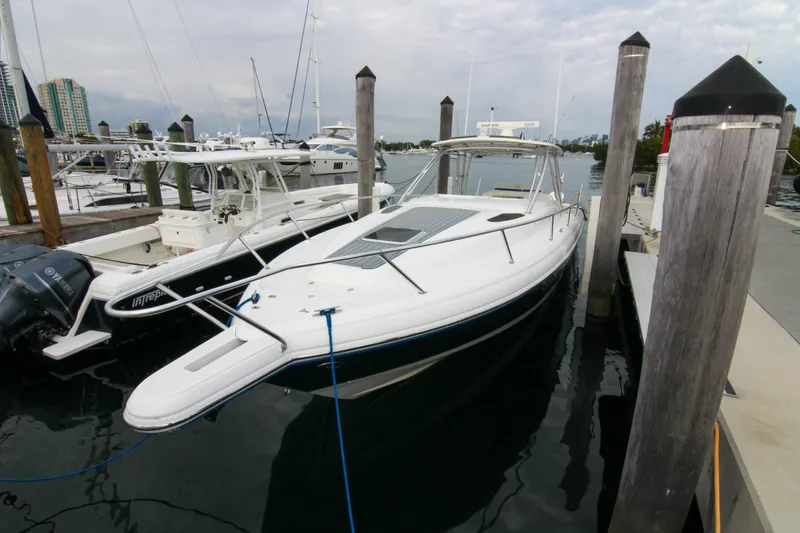Slide: The Image of 2003 Intrepid 377 Walkaround boat docked at marina, surrounded by other vessels. - 16