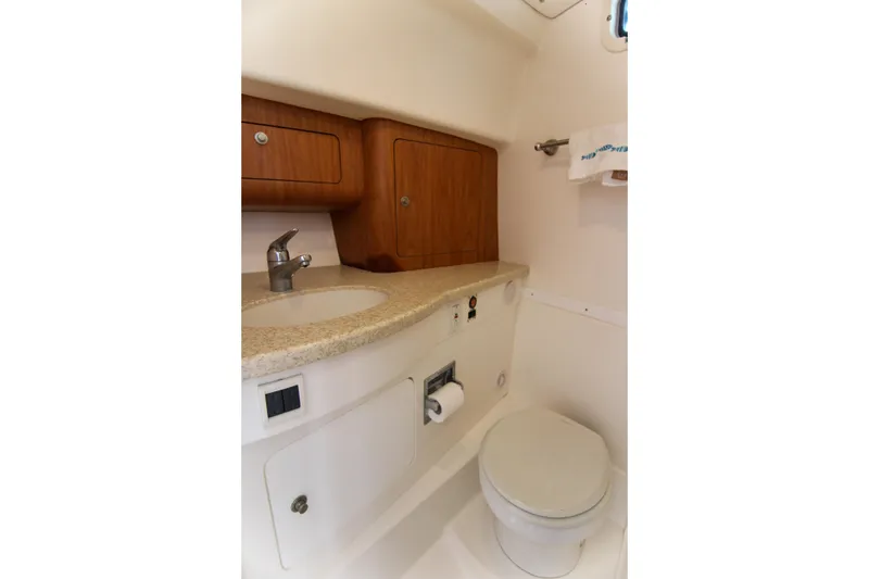 Slide: The Image of 2003 Intrepid 377 Walkaround boat bathroom with sink, toilet, and wooden cabinets. - 25