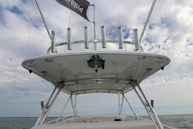 Slide: The Image of 2003 Intrepid 377 Walkaround boat with rod holders and canopy, under a cloudy sky. - 36