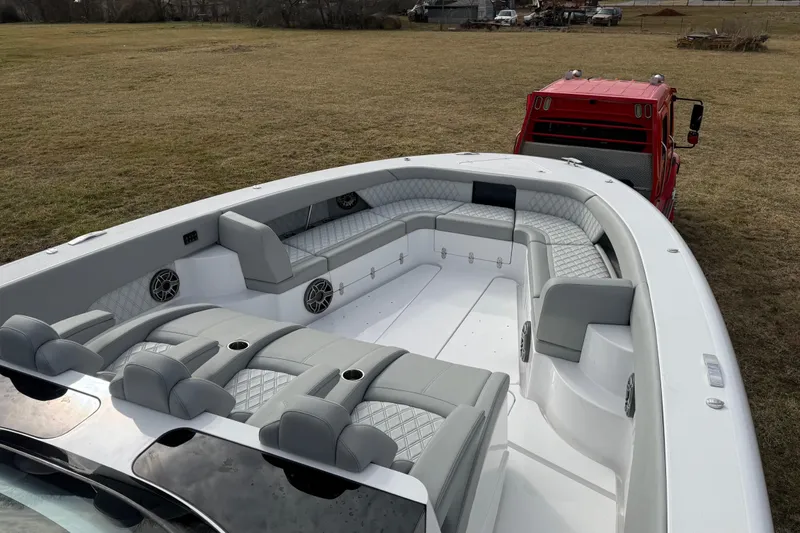 Slide: The Image of 2023 Mystic Powerboats M5200 with luxurious seating, parked on grass beside a red vehicle. - 23