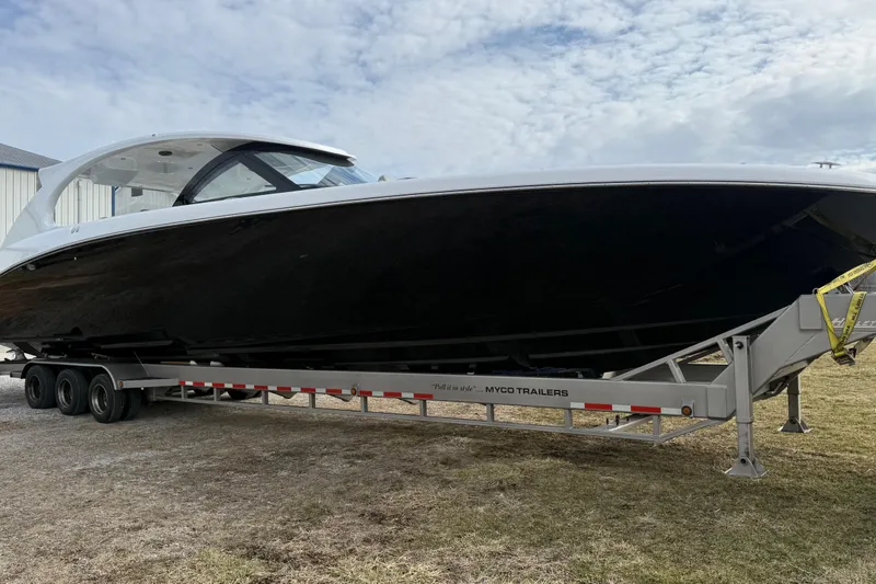 Slide: The Image of 2023 Mystic Powerboats M5200 on trailer, sleek black hull, overcast sky background. - 8
