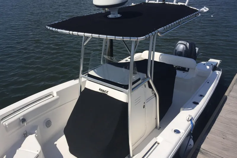Slide: The Image of 2013 Sea Fox 226 Commander boat docked, featuring a black T-top and console cover. - 12