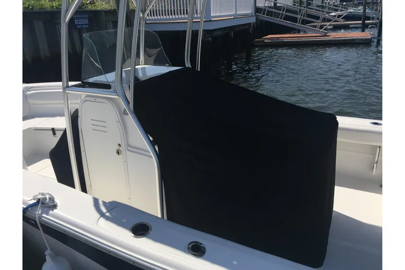 Slide: The Image of 2013 Sea Fox 226 Commander boat with black console cover, docked by the water. - 13