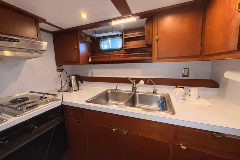 Slide: The Image of 1965 Custom Trawler kitchen with wooden cabinets, dual sink, and stovetop. - 10