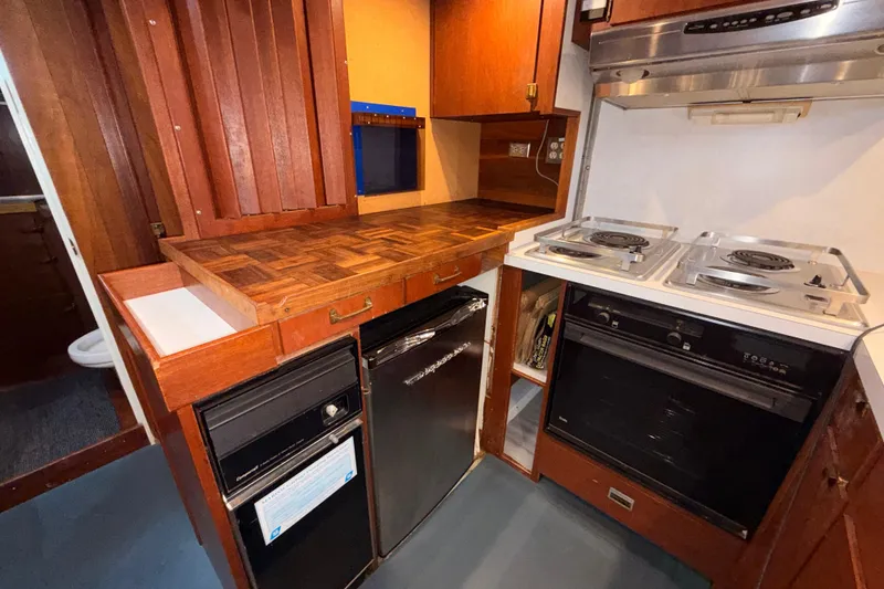 Slide: The Image of 1965 Custom Trawler kitchen with wood cabinetry, electric stove, and compact appliances. - 12