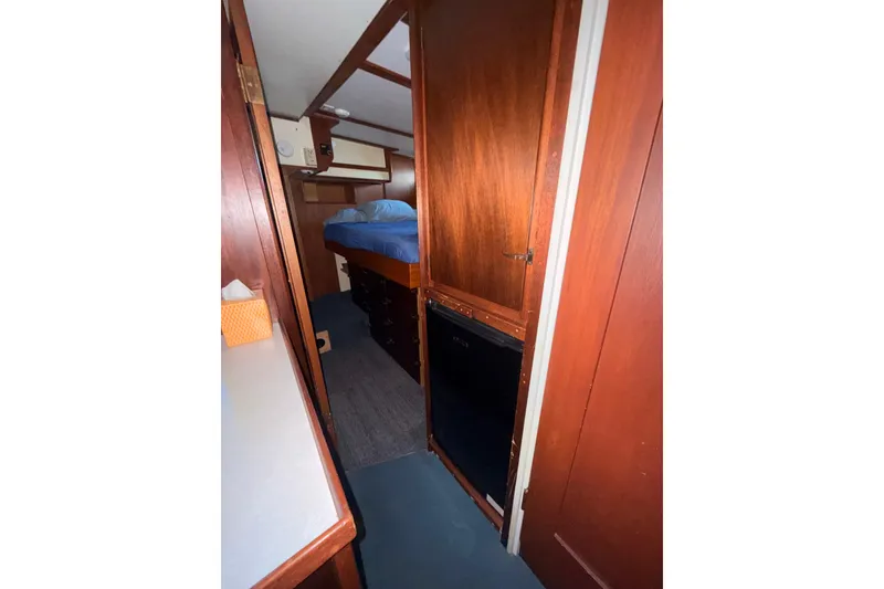 Slide: The Image of Interior of a 1965 Custom Trawler, featuring wooden cabinetry and a cozy sleeping area. - 14
