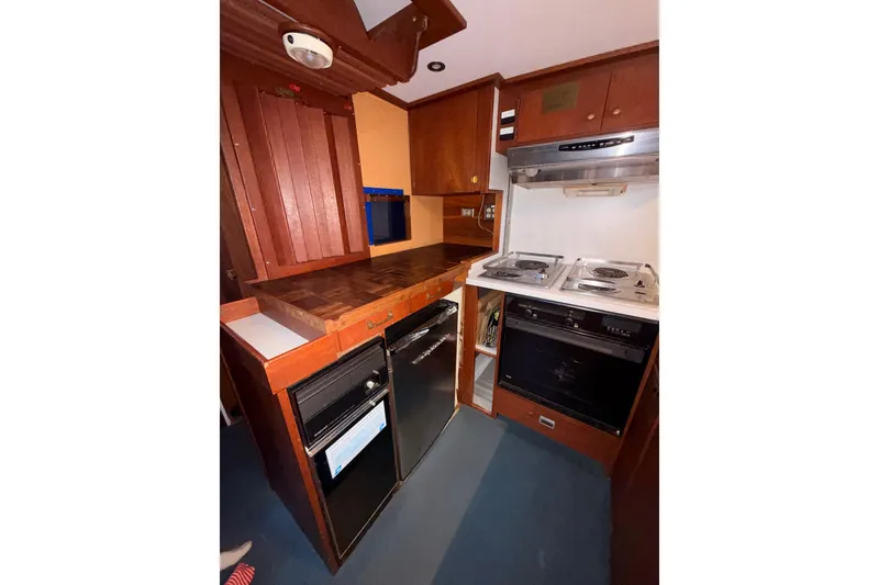 Slide: The Image of 1965 Custom Trawler kitchen with wood cabinetry, stove, and compact appliances. - 21
