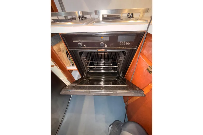 Slide: The Image of Open oven in a 1965 Custom Trawler kitchen, showcasing interior racks and controls. - 8