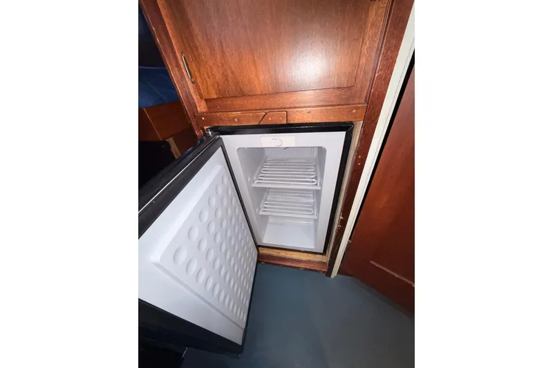 Slide: The Image of Open mini fridge inside a 1965 Custom Trawler, wooden cabinetry visible. - 9