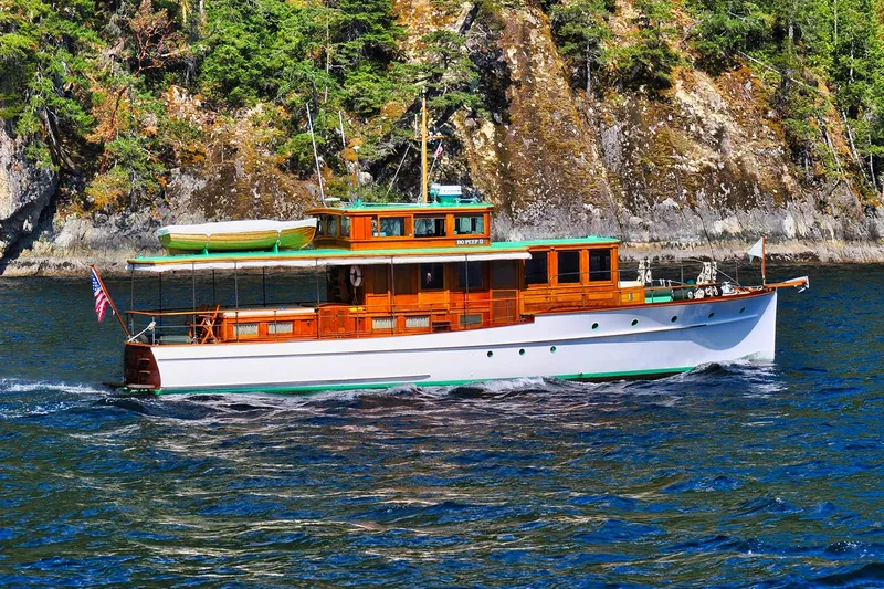 Slide: The Image of 1926 Hacker-Craft Bridge Deck yacht cruising near rocky coastline. - 2