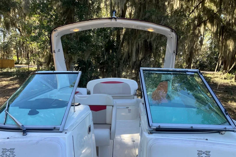 Slide: The Image of 2015 Chaparral 287 SSX boat interior with open windshield, surrounded by lush greenery. - 13