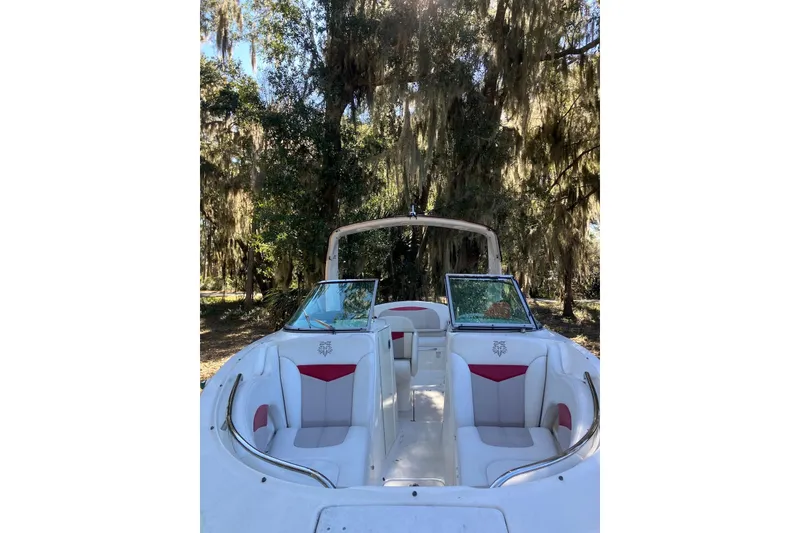 Slide: The Image of 2015 Chaparral 287 SSX boat interior with white and red seating, surrounded by trees. - 17