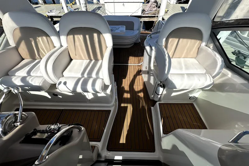 Slide: The Image of 2003 Sea Ray 340 Sundancer cockpit with white seats and wooden flooring. - 10