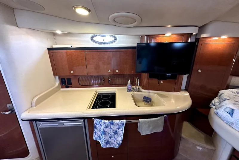 Slide: The Image of 2003 Sea Ray 340 Sundancer interior with kitchenette, sink, stove, and mounted TV. - 18
