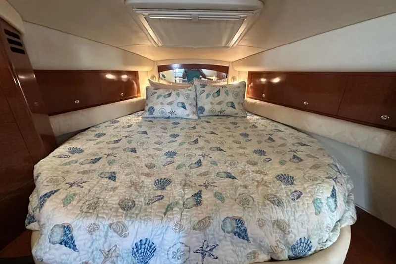 Slide: The Image of 2003 Sea Ray 340 Sundancer cabin with seashell-themed bedding and wooden storage cabinets. - 19