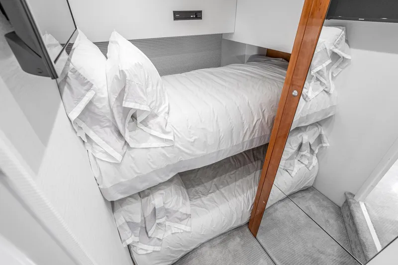 Slide: The Image of Bunk beds in 2021 Sunseeker Predator 68 yacht cabin, featuring white linens and wooden accents. - 71