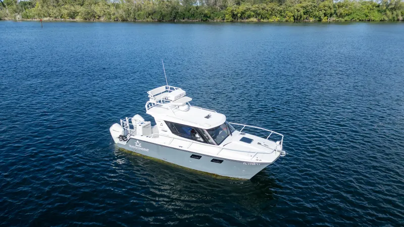 Slide: The Image of 2023 ArrowCat Flybridge Dual Helm boat on calm water, surrounded by lush greenery. - 12