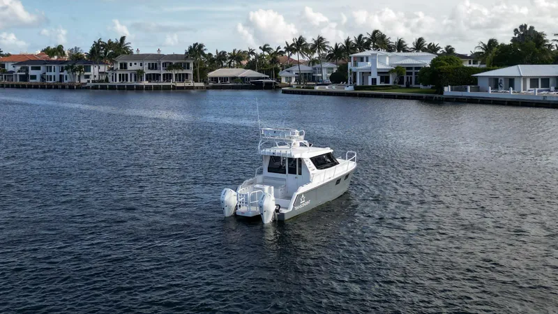 Slide: The Image of 2023 ArrowCat Flybridge Dual Helm boat on a serene waterfront with luxury homes. - 14