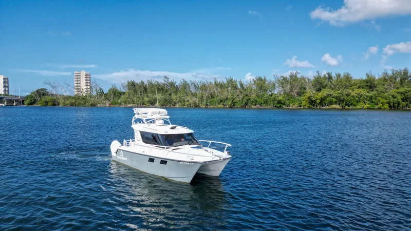 Slide: The Image of 2023 ArrowCat Flybridge Dual Helm cruising on a serene lake under a clear blue sky. - 17