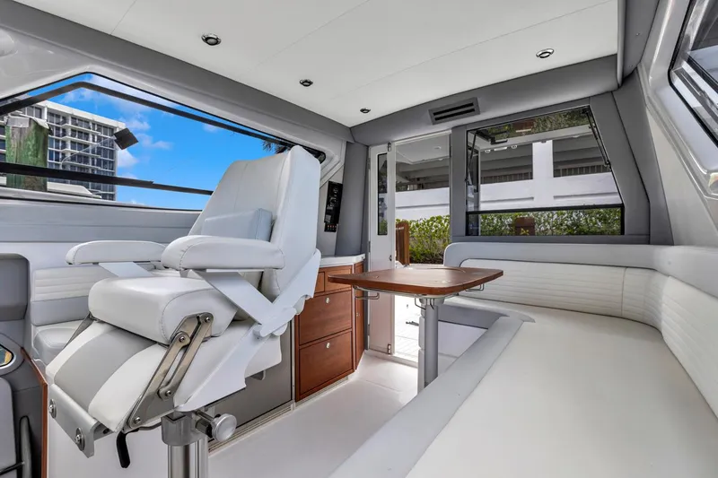Slide: The Image of 2023 ArrowCat Flybridge Dual Helm interior with white seating and wooden table. - 48