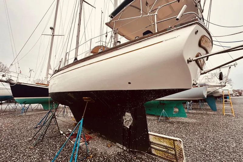 Slide: The Image of 1978 Shannon 38 sailboat on dry dock, supported by stands, with visible hull and rudder. - 4