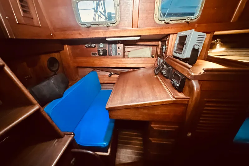 Slide: The Image of Interior of a 1978 Shannon 38 sailboat with navigation station and blue seating. - 9