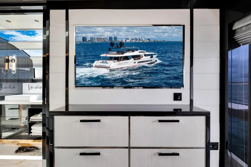Slide: The Image of Interior of Sirena 88 yacht, 2021 model, featuring a wall-mounted TV displaying a yacht at sea. - 76