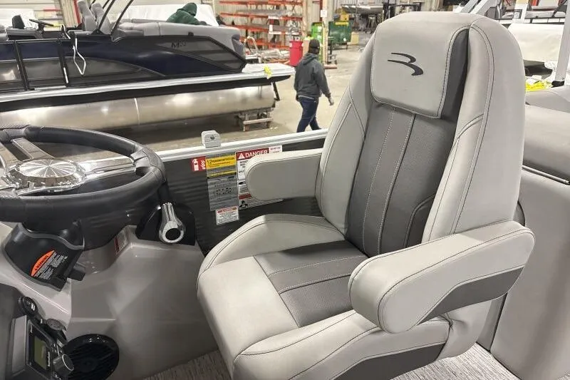 Slide: The Image of Captain's chair and steering wheel of 2026 Bennington 22SXSR pontoon boat in a showroom. - 8