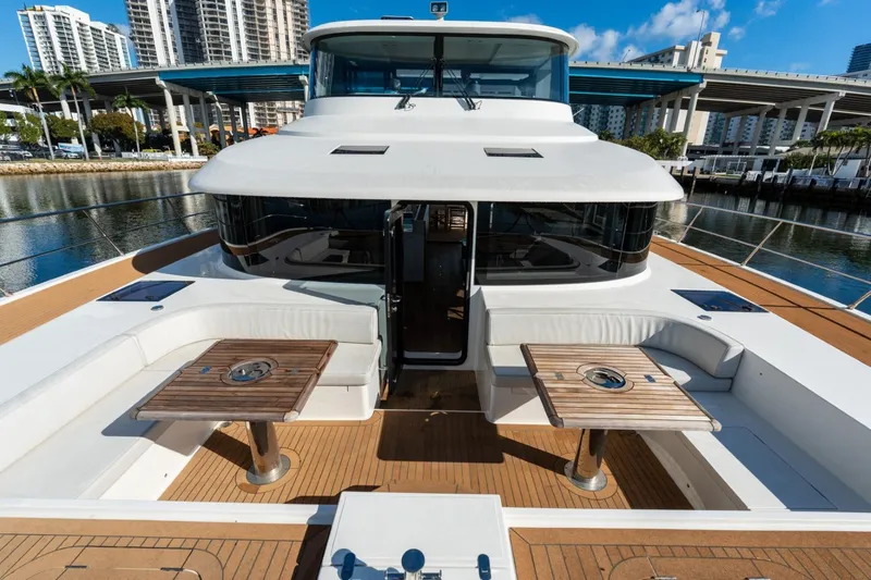Slide: The Image of Luxurious 2023 Granocean 57 yacht with elegant deck seating and wooden tables, docked in a marina. - 53