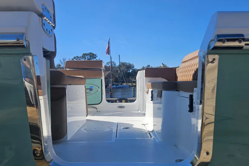 Slide: The Image of 2026 Sea Hunt Ultra 275 Coffin Box boat interior with seating, docked by a lake. - 10
