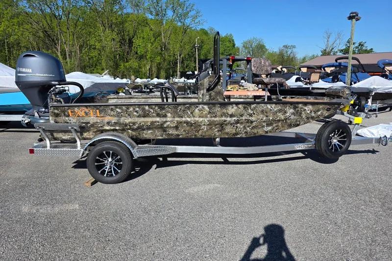 The Image of 2026 Excel Switchblade boat with camouflage design on a trailer, parked outdoors. - 16
