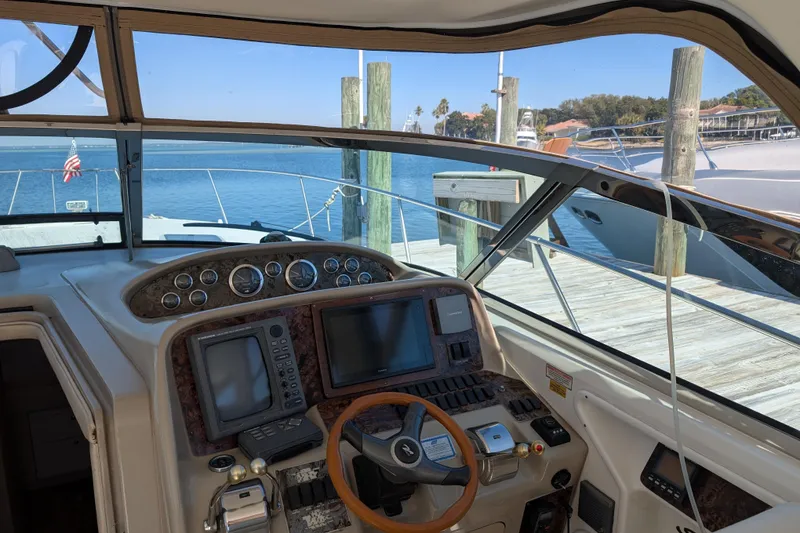 Slide: The Image of 1999 Sea Ray 370 Express Cruiser helm with navigation equipment, docked by a serene waterfront. - 21