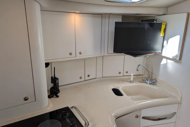 Slide: The Image of 1999 Sea Ray 370 Express Cruiser kitchen with sink, cabinets, and mounted TV. - 25