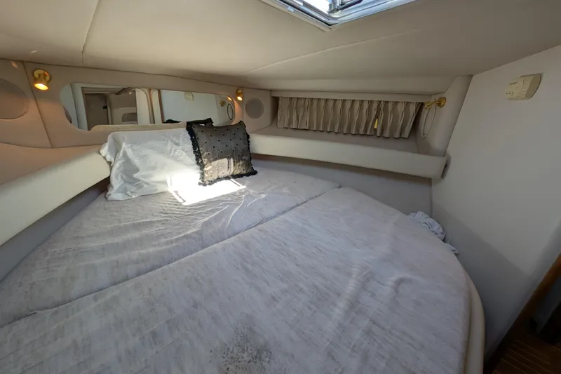 Slide: The Image of 1999 Sea Ray 370 Express Cruiser cabin with bed, pillows, and window. - 28
