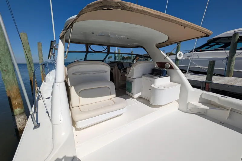 Slide: The Image of 1999 Sea Ray 370 Express Cruiser interior with seating and helm, docked by the water. - 7
